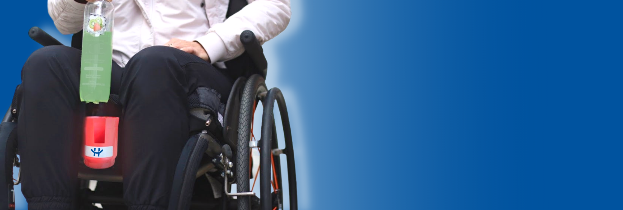 an image of a person in a wheel chair easily putting a drink into their HandiCup 